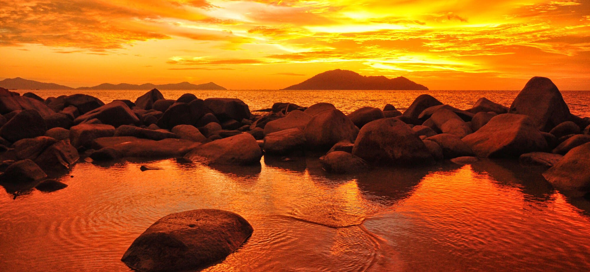 Watery pool of water in front of a large lake bathed in orange sunlight